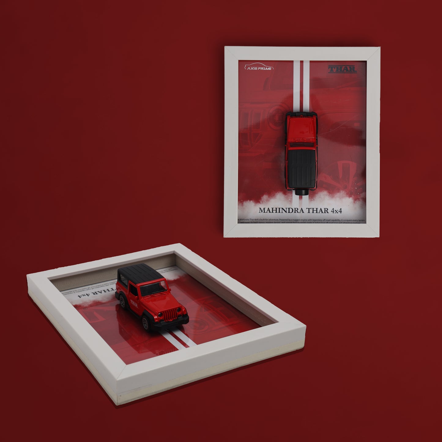 Red model car in a white frame on a red background with a framed picture of a Mahindra Thar 4x4 vehicle.