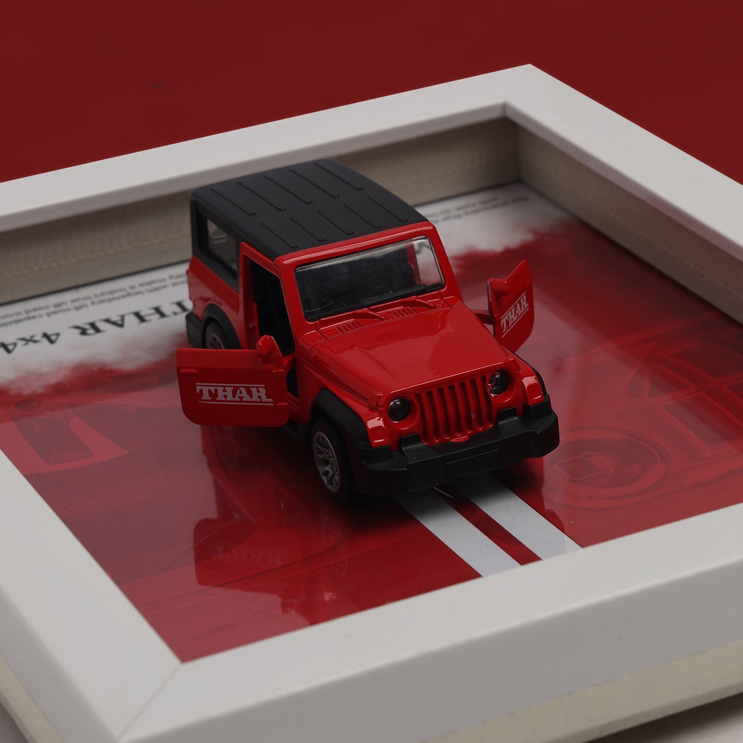 Red toy jeep with black roof on a reflective surface
