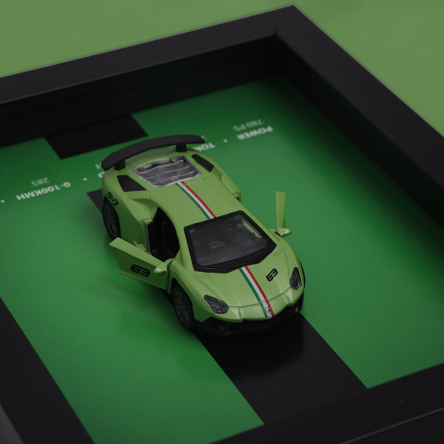Green toy car on a green surface with a black frame
