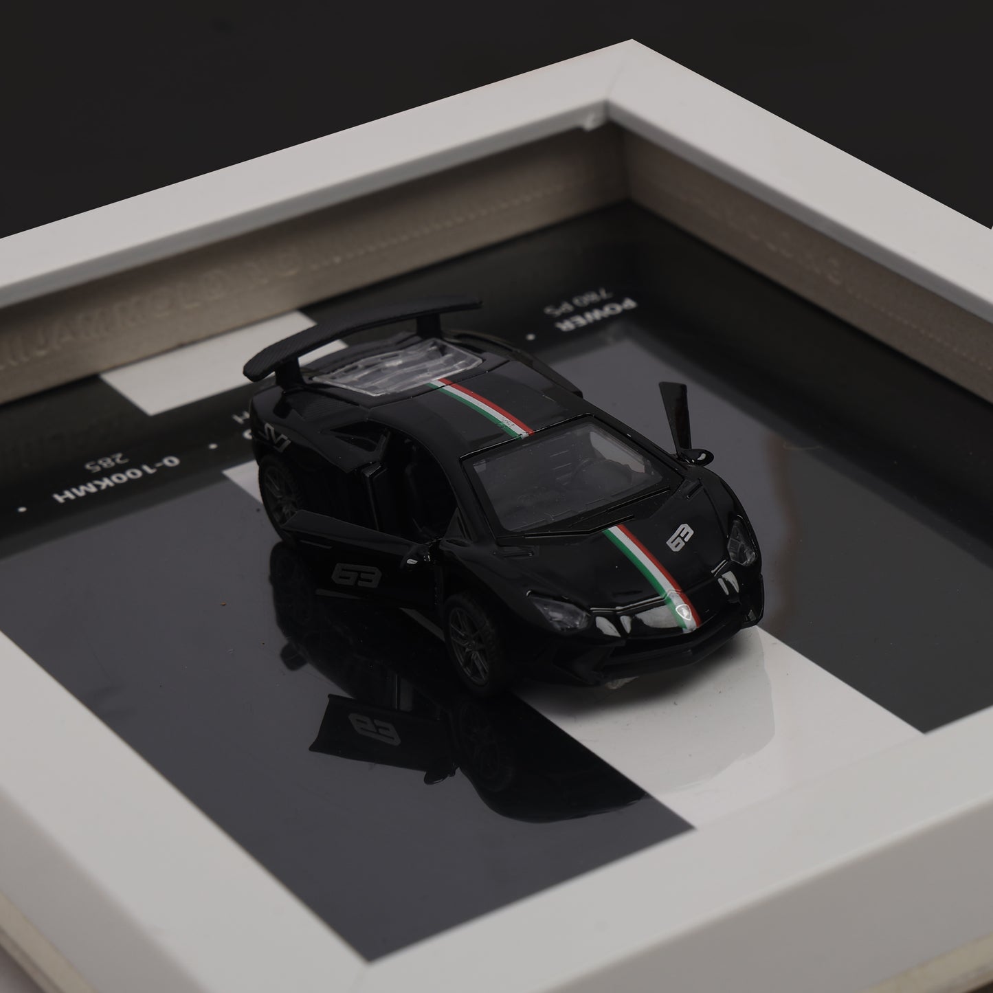 Black model car with red and green stripes on a reflective surface