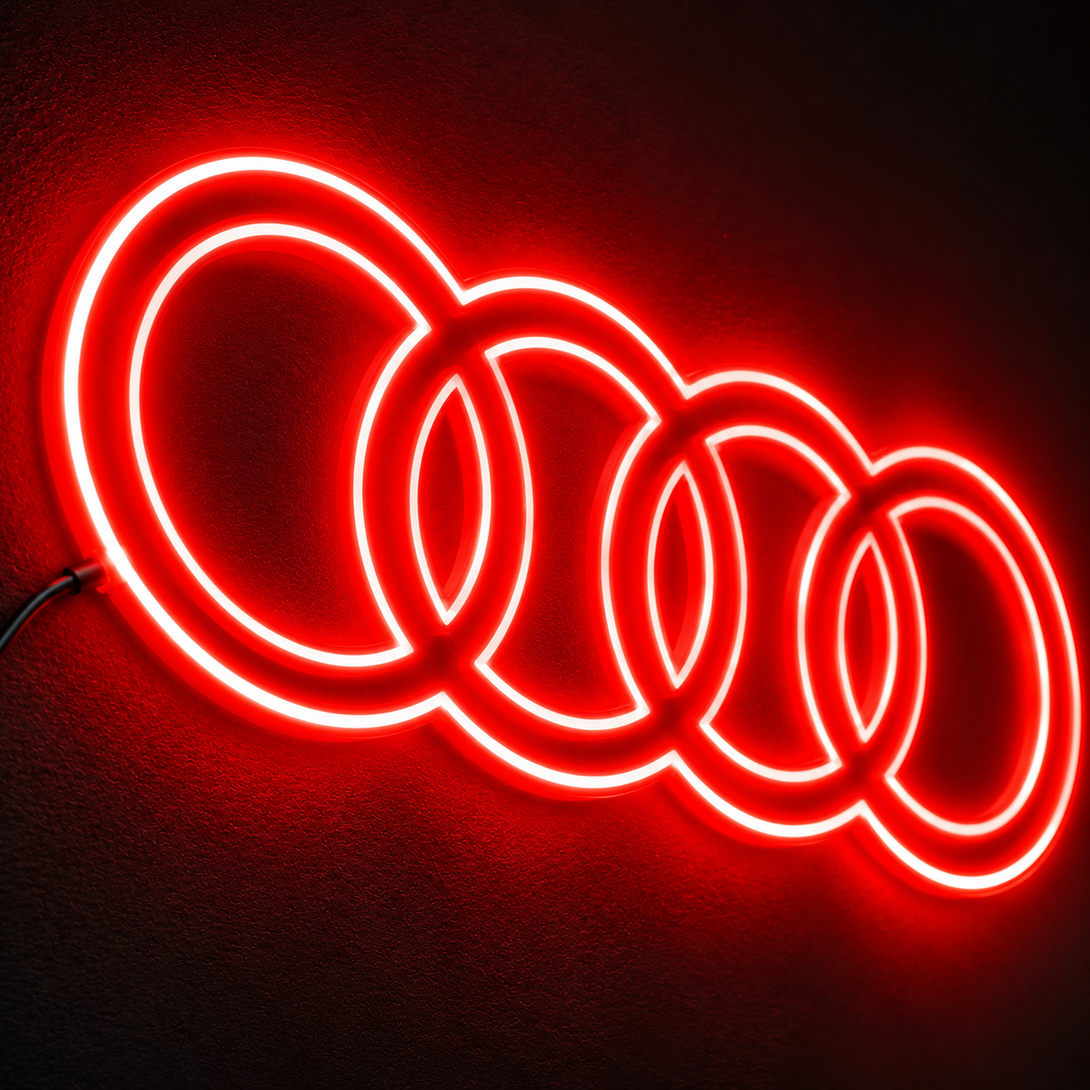 Audi four-ring logo LED wall sign glowing blue against a dark brick wall