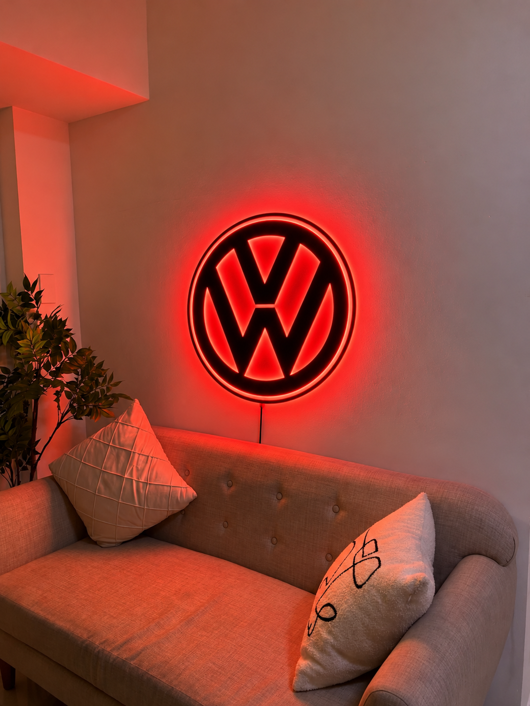 Volkswagen VW logo LED wall sign with warm yellow backlighting on a dark wall, automotive decor for garages and car enthusiasts.