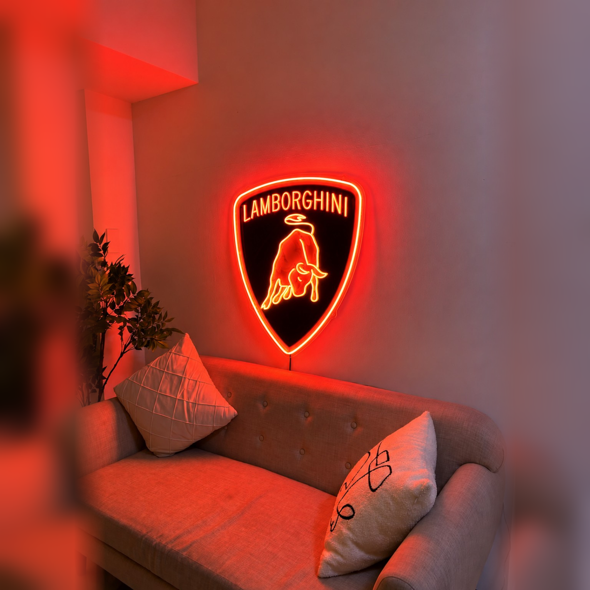 Lamborghini shield logo LED wall sign glowing yellow above a sofa in a modern living room